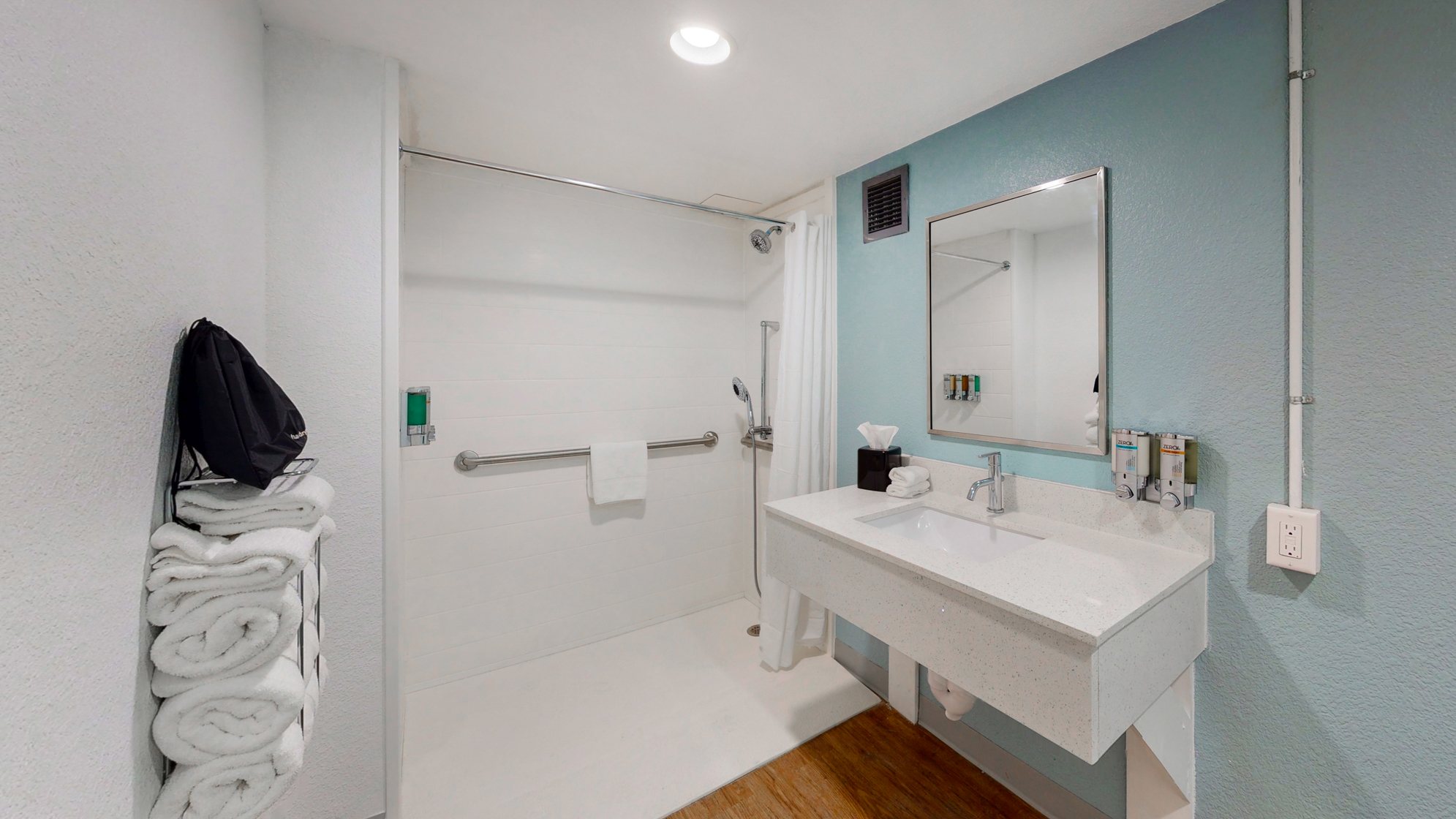 Accessible private bathroom in guest room with roll-in shower and roll under vanity.